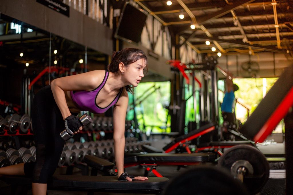 Woman in the gym doing a single arm dumbbell bent over row